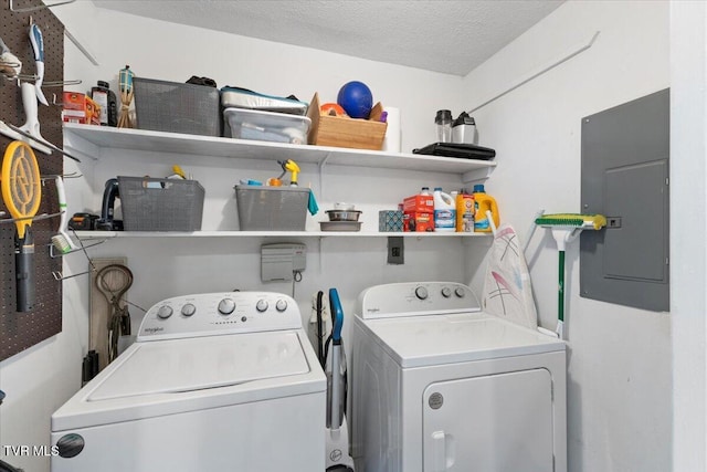 clothes washing area with laundry area, electric panel, a textured ceiling, and washing machine and clothes dryer