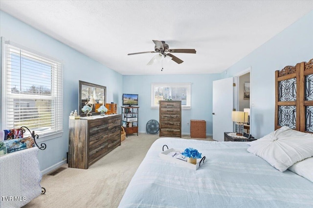 bedroom with light carpet, a ceiling fan, visible vents, and baseboards