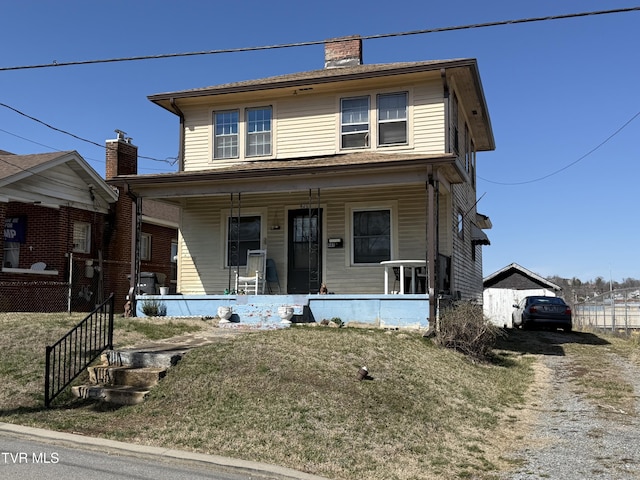 american foursquare style home with a porch, driveway, a chimney, and a front lawn