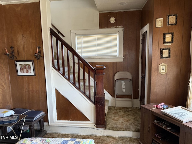 staircase with wood walls and carpet flooring