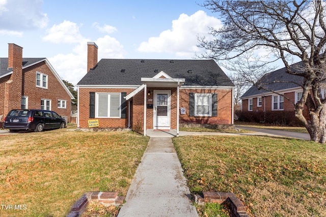 bungalow-style home featuring a shingled roof, a front yard, brick siding, and a chimney