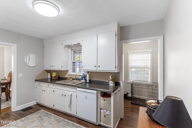 kitchen with dark countertops, a healthy amount of sunlight, white dishwasher, and visible vents