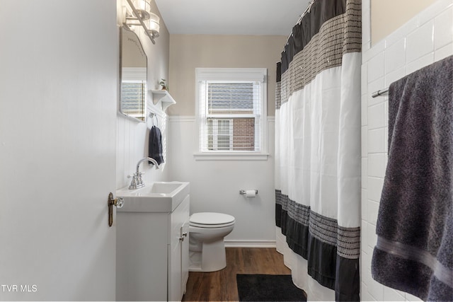 bathroom featuring wainscoting, toilet, a shower with curtain, wood finished floors, and vanity