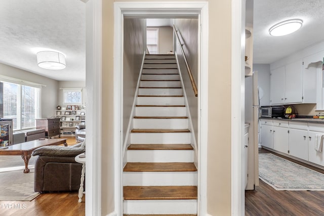 staircase featuring a textured ceiling and wood finished floors