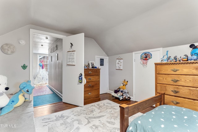 bedroom with vaulted ceiling, baseboards, and wood finished floors