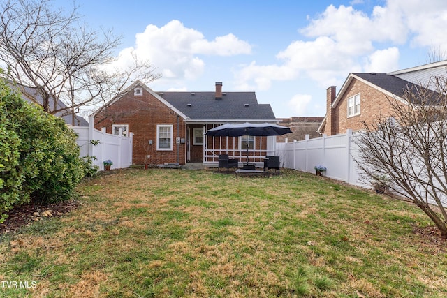 rear view of property with a fenced backyard, a lawn, and brick siding