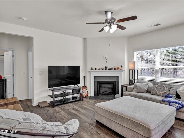 living area with dark wood-style floors, ceiling fan, a fireplace, and visible vents