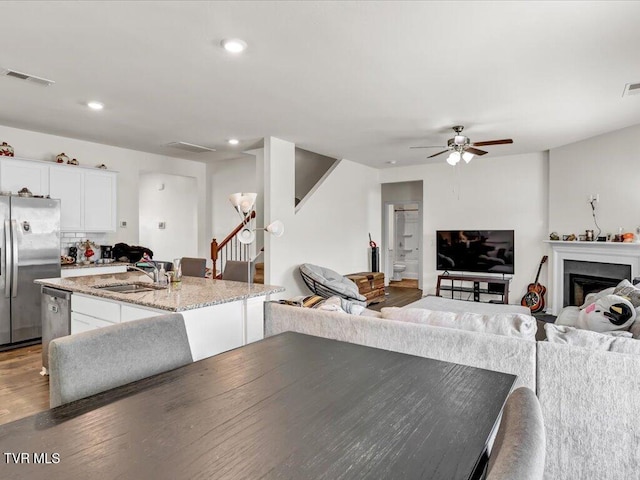 dining area featuring recessed lighting, a fireplace, wood finished floors, visible vents, and stairs