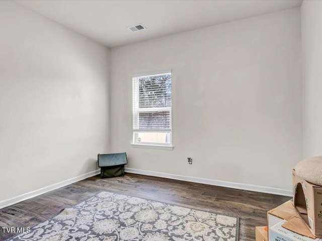 unfurnished room with baseboards, visible vents, and wood finished floors