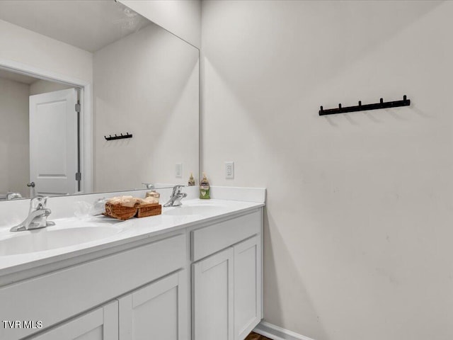 bathroom with double vanity, a sink, and baseboards