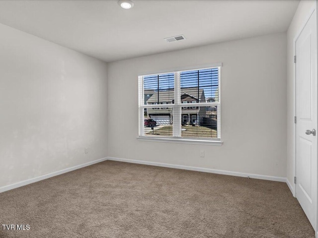 unfurnished room with carpet, visible vents, and baseboards