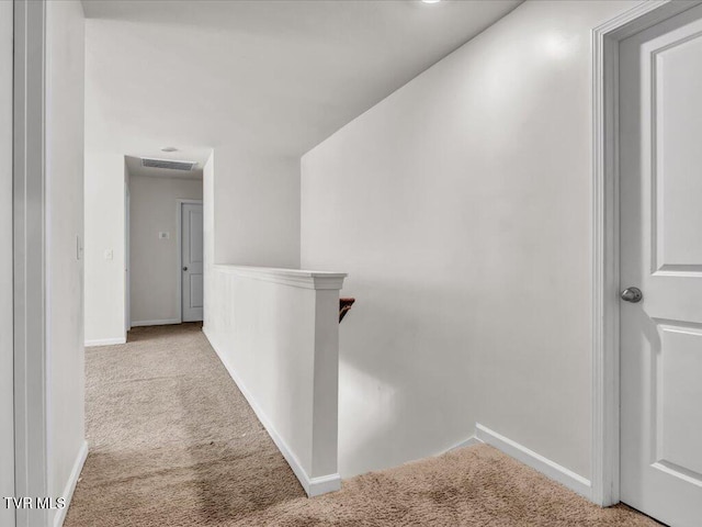 hallway with visible vents, baseboards, carpet flooring, and an upstairs landing