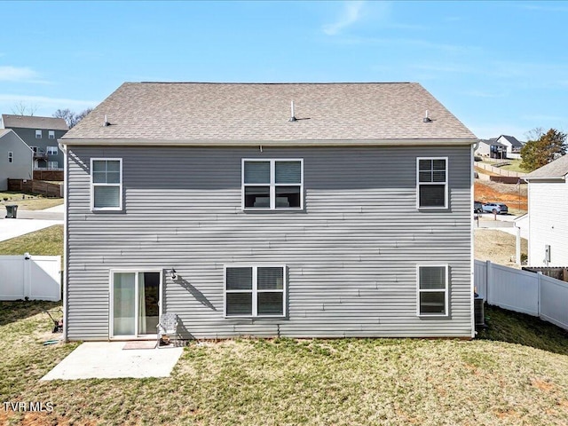 rear view of house featuring a patio area, a fenced backyard, a lawn, and roof with shingles