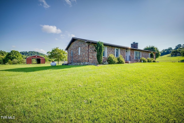 ranch-style home with brick siding, a chimney, a pole building, and a front yard