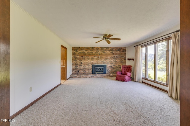 unfurnished living room with a ceiling fan, a brick fireplace, carpet flooring, a textured ceiling, and baseboards