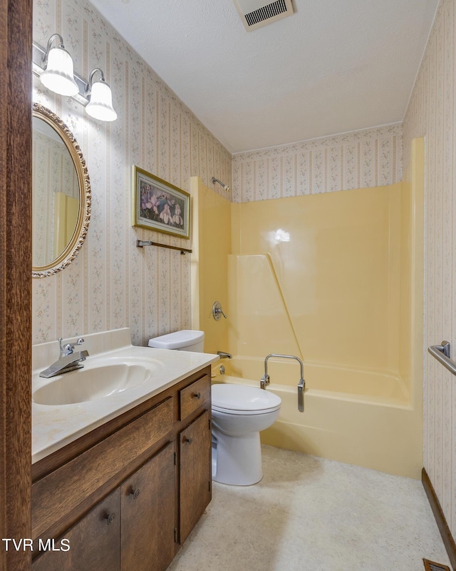 bathroom featuring toilet, vanity, washtub / shower combination, and wallpapered walls