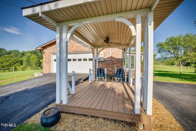 wooden terrace with a garage, a yard, ceiling fan, and a porch