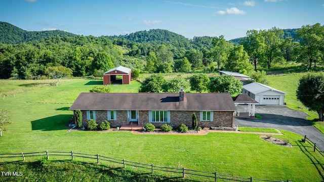 exterior space featuring a forest view, a front lawn, an outdoor structure, and fence