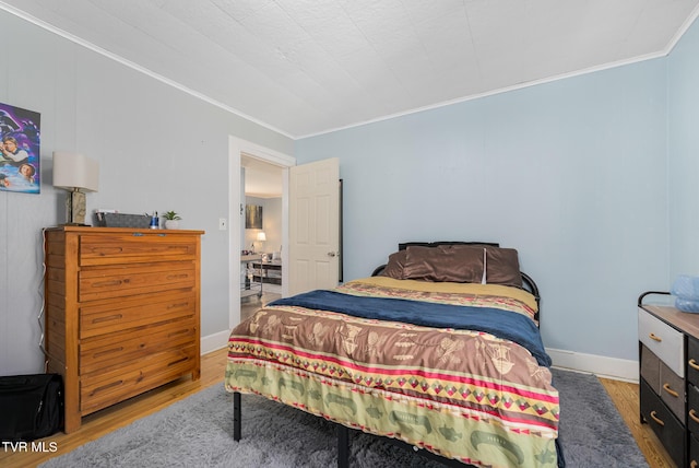 bedroom featuring baseboards, wood finished floors, and crown molding