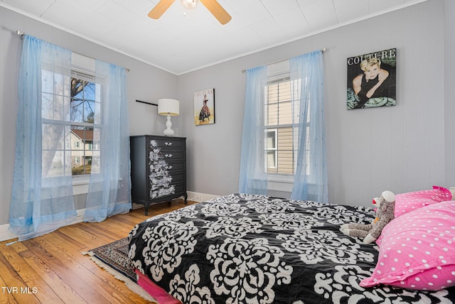 bedroom with a ceiling fan, baseboards, ornamental molding, and wood finished floors