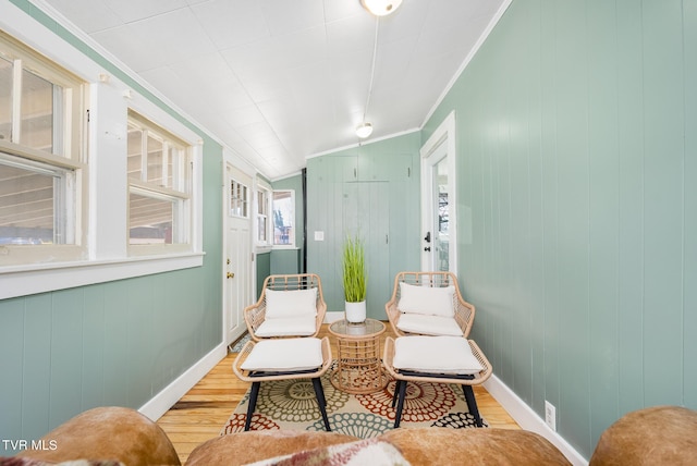 sitting room featuring light wood-style floors, lofted ceiling, crown molding, and baseboards