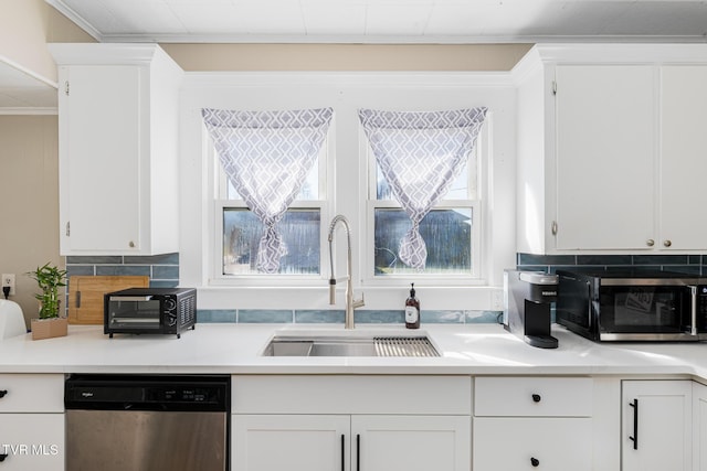 kitchen with stainless steel appliances, tasteful backsplash, a sink, and white cabinetry