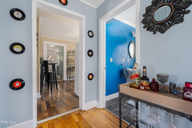 corridor with ornamental molding, hardwood / wood-style flooring, and baseboards