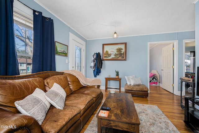 living area featuring ornamental molding, a wealth of natural light, baseboards, and wood finished floors