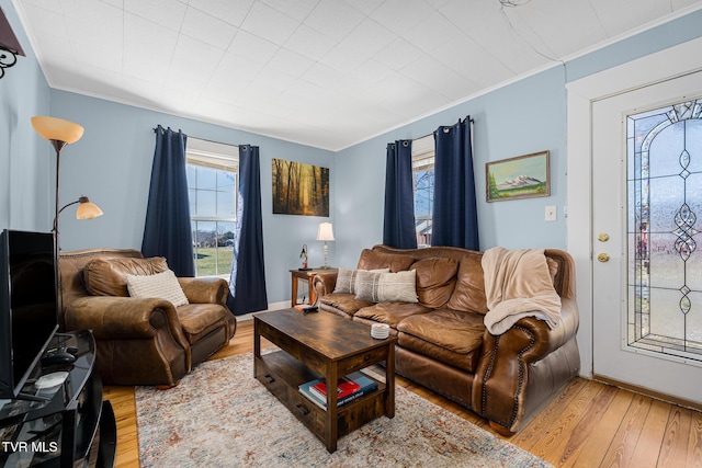 living area featuring light wood-style flooring, baseboards, and crown molding