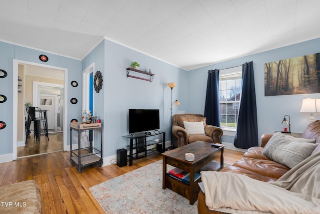 living area with baseboards, ornamental molding, and wood finished floors