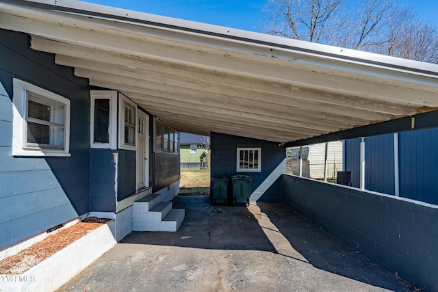 view of parking with an attached carport, driveway, and fence