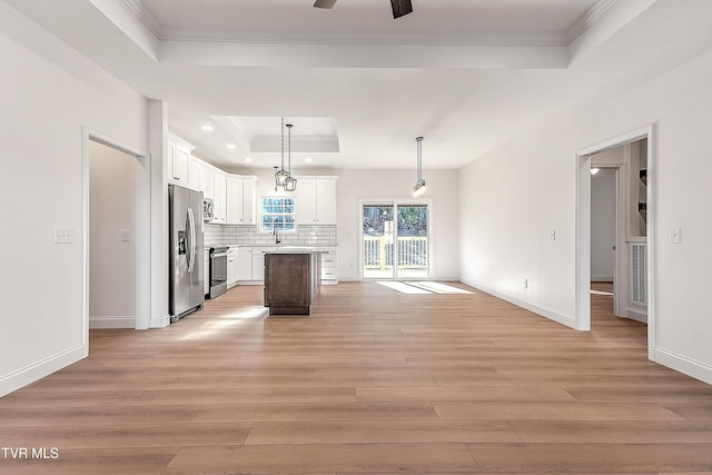 kitchen with tasteful backsplash, a center island, a tray ceiling, stainless steel appliances, and light wood-style floors