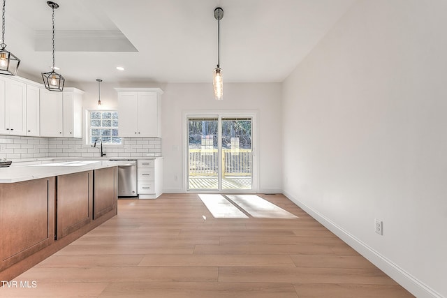 kitchen featuring light countertops, decorative backsplash, light wood-style floors, plenty of natural light, and dishwasher