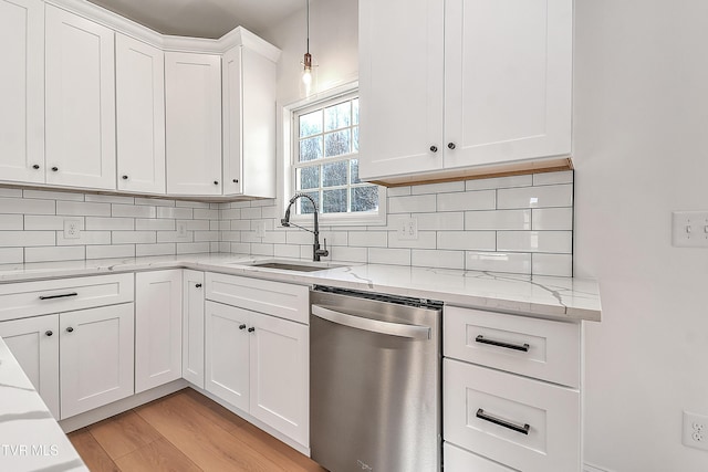 kitchen featuring a sink, light wood-style floors, white cabinets, stainless steel dishwasher, and tasteful backsplash