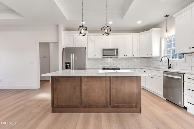 kitchen featuring stainless steel appliances, a raised ceiling, light wood-style floors, and tasteful backsplash