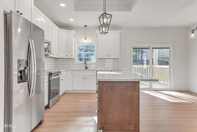 kitchen with stainless steel appliances, a kitchen island, a sink, light wood-style floors, and backsplash