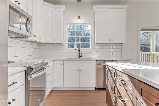 kitchen featuring light stone counters, stainless steel appliances, a sink, white cabinets, and light wood-style floors