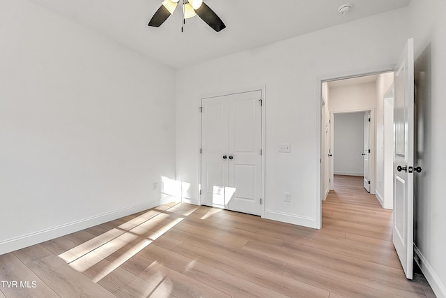 unfurnished bedroom with light wood-style floors, a ceiling fan, baseboards, and a closet