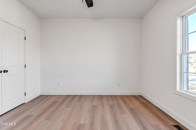 empty room featuring light wood-style floors, visible vents, and a wealth of natural light