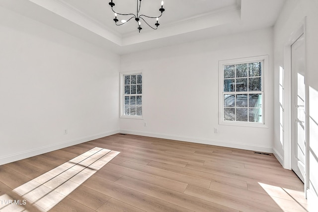 unfurnished room with light wood-style floors, baseboards, a tray ceiling, and a chandelier