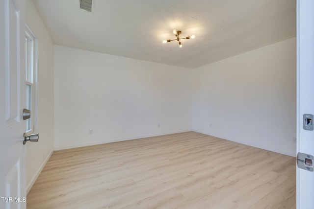 empty room featuring visible vents, baseboards, and light wood-style flooring