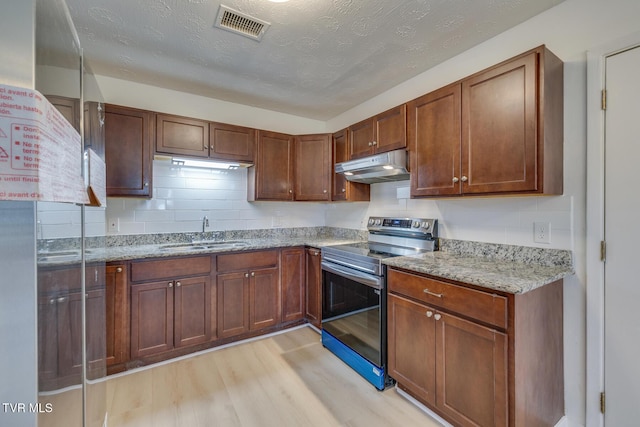 kitchen featuring visible vents, light wood-style flooring, stainless steel electric stove, a sink, and under cabinet range hood