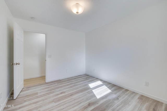 spare room with baseboards and wood finished floors