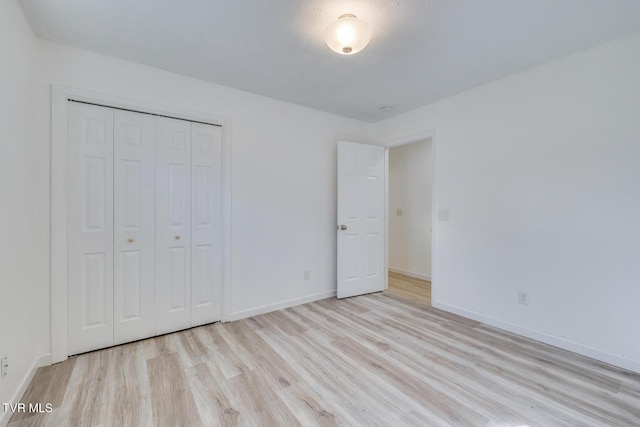 unfurnished bedroom featuring a closet, baseboards, and wood finished floors