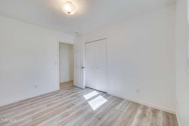 unfurnished bedroom featuring a closet, light wood-style flooring, and baseboards