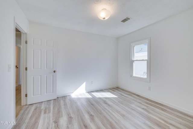 empty room with visible vents, baseboards, and light wood-style flooring