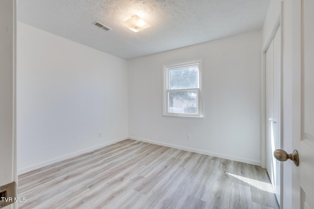 unfurnished bedroom with baseboards, wood finished floors, visible vents, and a textured ceiling