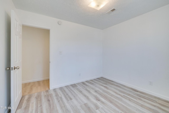 empty room featuring visible vents, a textured ceiling, baseboards, and wood finished floors