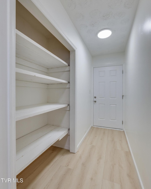 doorway to outside with baseboards, a textured ceiling, and wood finished floors