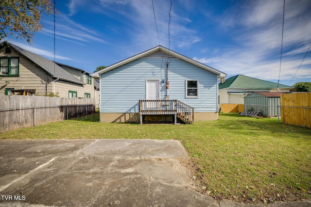 back of property with a lawn and fence